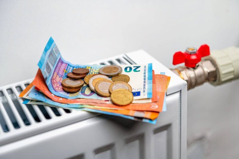 Na kaloryferze leżą euro symbolizujące dopłatę za ciepło.