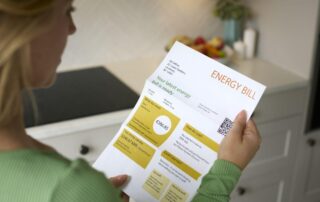 Osoba trzyma rachunek za energię, który uwzględnia współczynnik wyrównawczy LAF.